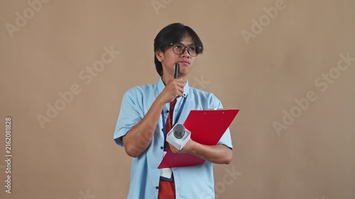 Asian male reporter thinking and getting idea while writing on clipboard holding microphone in studio