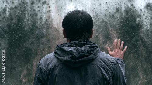 Back view of man standing in front of a moldy wall  