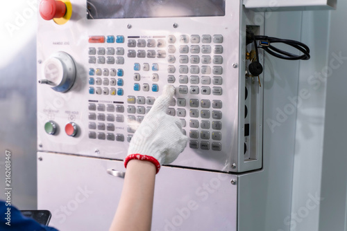 Closeup hand of technician Engineer in a working grove touch, press the button of automated cnc machinery control panel in an industrial workshop.