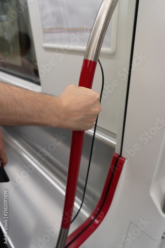 Canvastavla Hand gripping pole in subway train interior