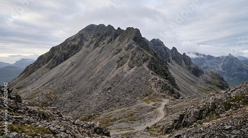 Majestic Rocky Mountain Peak with a Winding Hiking Trail Under a Moody Overcast Sky in a Wild High Altitude Landscape