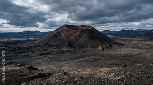 Cinematic View of a Massive Volcanic Crater in a Barren Lava Field Under a Dark Dramatic Stormy Cloudy Sky at Dusk
