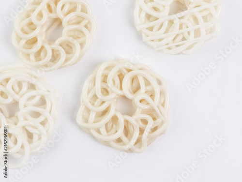 Close-up top-down view of several raw, uncooked white kerupuk (Indonesian crackers or prawn crackers) arranged on a clean white background, highlighting their intricate coiled and looped textures.