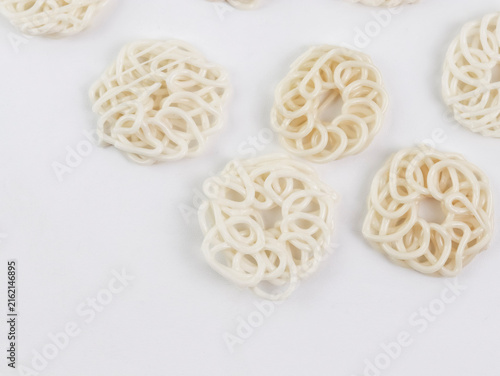 Detailed top-down view of multiple raw, uncooked white kerupuk (Indonesian crackers) scattered creatively across a clean white background.