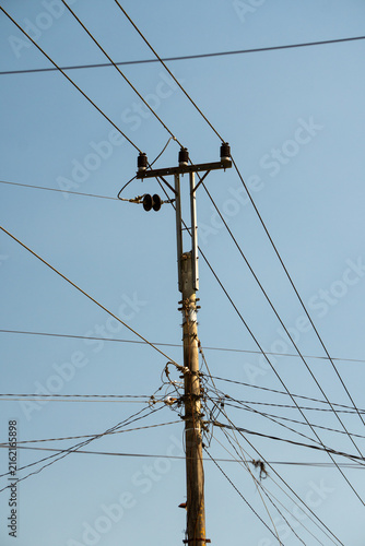 Bild auf Leinwand Utility pole supporting overhead electrical distribution lines against a clear blue sky