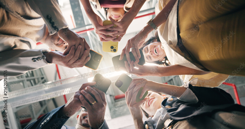 Obraz premium Below, phone and group of business people in circle with connection, online and social media post. Happy men, women and technology in office for community, ux survey or feedback for company policy
