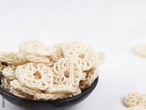 Close-up horizontal product shot of a black bowl filled with raw white kerupuk udang (traditional Indonesian prawn crackers)