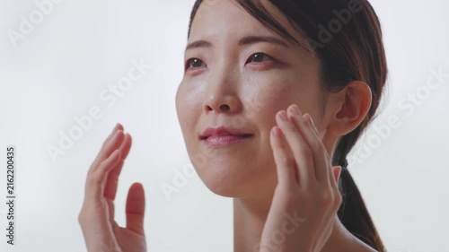 両手で頬を包み潤いを実感する笑顔の女性