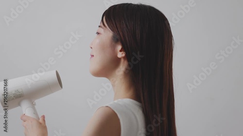 横向きでドライヤーの風を髪に当てる女性
