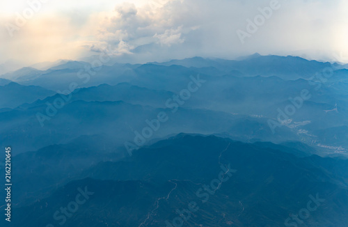 aerial view of mountain range in fog and great wall on mountain ridge