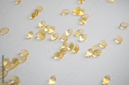 Yellow vitamin capsules scattered on white background, representing fat soluble vitamins, vitamin D, dietary supplements, health, nutrition and sunshine vitamin concept Health care concept