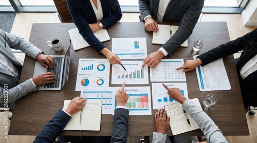 Top view of diverse business team analyzing financial charts and graphs at conference table, strategic planning meeting, corporate management discussion, data analysis