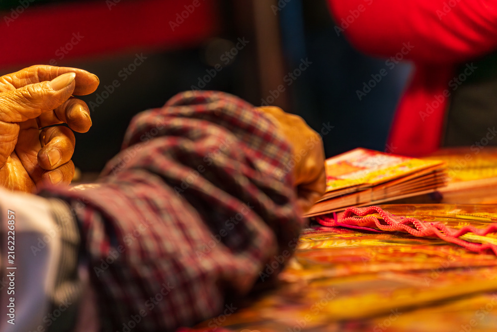 Obraz premium Taipei, Taipei City/Taiwan - 02/04/2026: Hands and coin scratching an instant lottery ticket under warm market light.