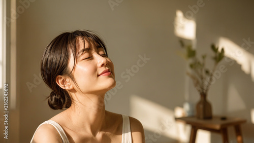 Fototapeta 目を閉じ柔らかな朝日の光を浴びて瞑想している若い日本人女性、リラックスした表情