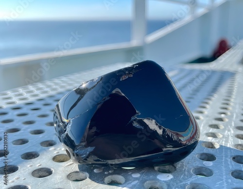 Obsidian Stone on Perforated Metal Ship Deck with Sea and Sky in Background