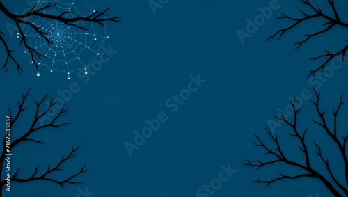 Spooky spider web on bare tree branches against a dark blue night sky background