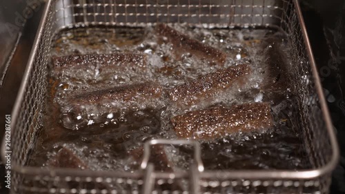 Close-up of sliced black bread, fried in boiling oil, deep-fried in a restaurant kitchen. Snacks are made at the bar, fast food, a beer plate.