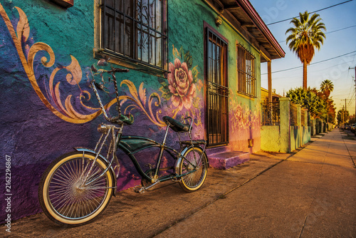 A lowrider bicycle leaning against a colorful stucco wall.