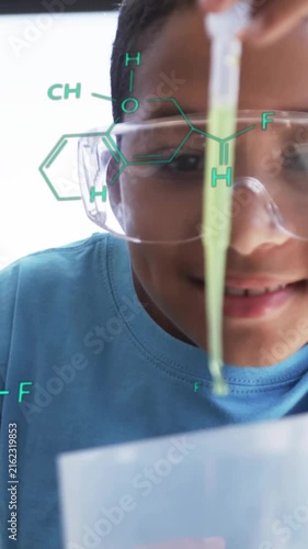Conducting science experiment, child with safety goggles over chemical formulas