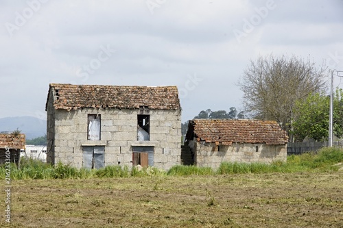Abandoned rural stone houses showing decay in a field. Portugal - Norte