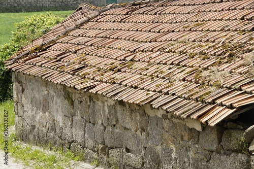 Old rural stone building with weathered roof tiles. Portugal - Norte