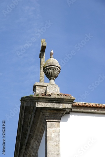 Stone cross with a bird on a church urn. Portugal - Norte