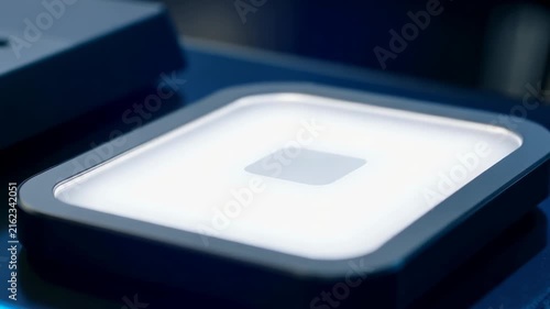 Hand placing colorful smartphone cover onto a charging pad, showcasing vibrant glitter design and illuminated surface in a modern tech environment