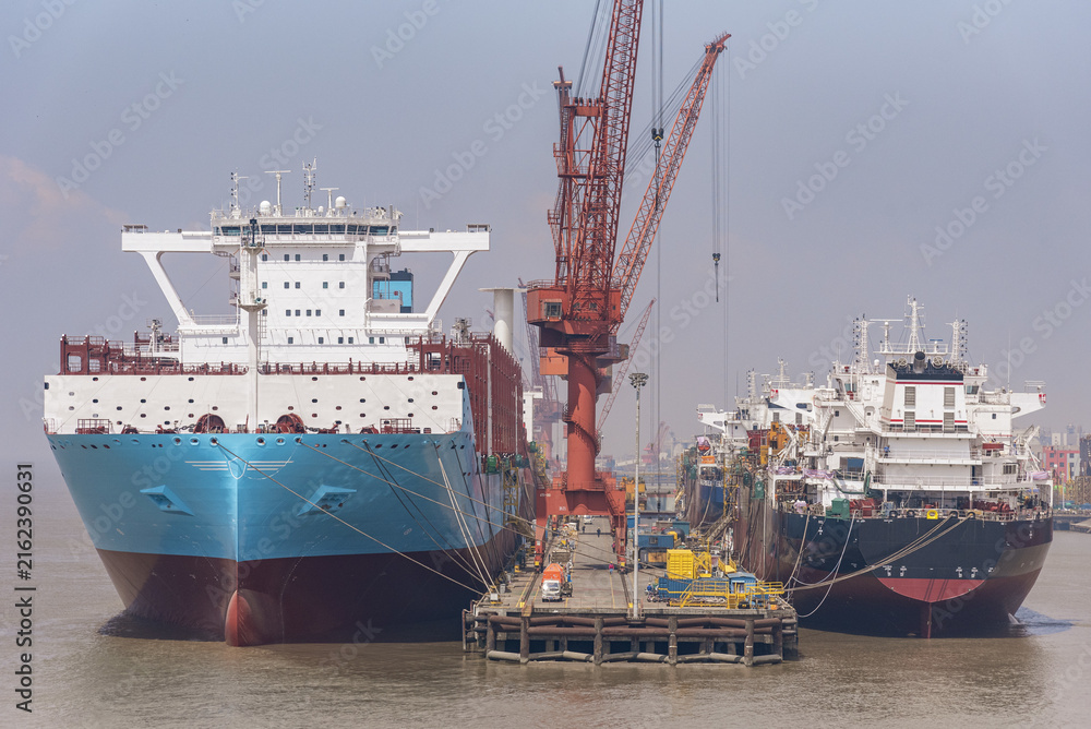 Fototapeta premium New ships berthed at a shipyard during the final phase of vessel completion, with the vessels being prepared for departure and their first voyage.