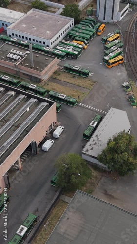 Aerial view of a green electric bus arriving at a charging depot in Milan, Italy, highlighting electric public transport, EV infrastructure and sustainable mobility.