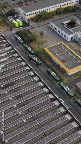 Aerial view of a green electric bus arriving at a charging depot in Milan, Italy, highlighting electric public transport, EV infrastructure and sustainable mobility.