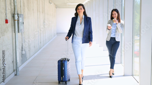 Businesswomen traveling through airport corridor during corporate trip