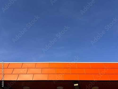 Bild auf Leinwand Low angle view of modern building roofline with bright orange panels against a c