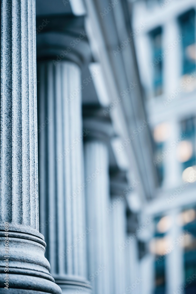 Fototapeta premium Majestic stone columns in front of a modern glass building representing law and finance