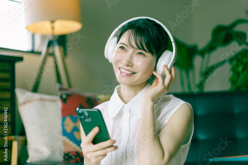 Fototapeta ヘッドフォンをつけてスマホで音楽を聴く若い日本人女性