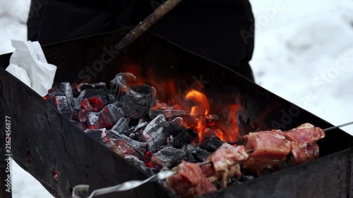 Meat roasts on charcoal barbecue. Skewers with meat grills on charcoal barbecue at outdoor picnic on freezing winter day