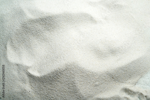 An overhead view of fine white sand showing natural wavy ripple patterns, creating a clean, minimalist texture. Summer, natural or texture background