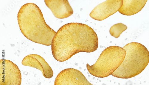 Cuadro en lienzo Crispy potato chips falling with sea salt crystals against a clean white background