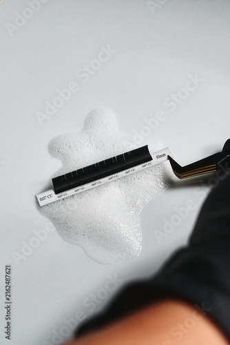 Fotografie Cleaning a lash tweezer in foam cleanser, close-up