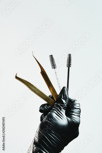 Lash extension tool kit: tweezers and brush held in hand