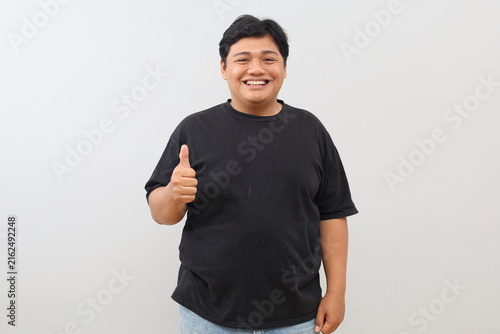 Foto A studio portrait of a heavy-set yet confident, cheerful, and enthusiastic man giving a thumbs-up gesture against a white background