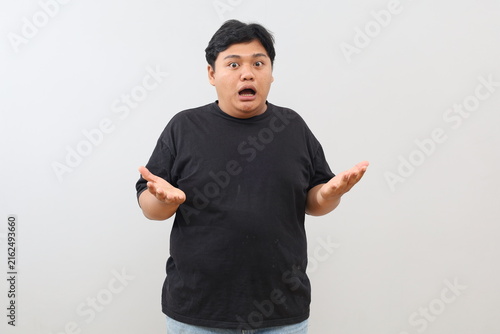 Foto A heavy-set Asian man appears confused with both arms raised, against a plain white background