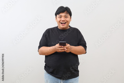 Obraz na plátne A heavy-set man appears both surprised and enthusiastic; he is holding a mobile phone and looking toward the camera against a plain white background