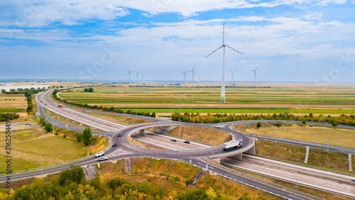 Fotografie Highway intersection with wind turbines in a rural landscape
