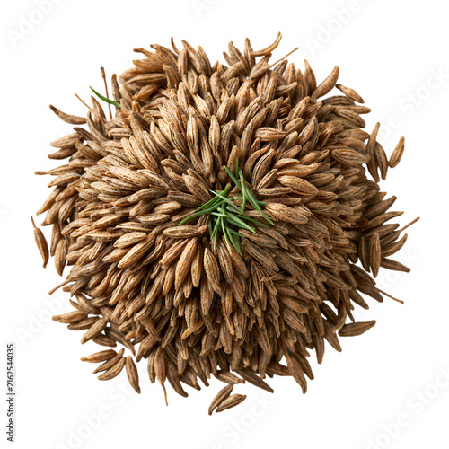 Cumin seeds pile with green herbs, dried caraway spice seeds on white background, organic aromatic seasoning for culinary cooking