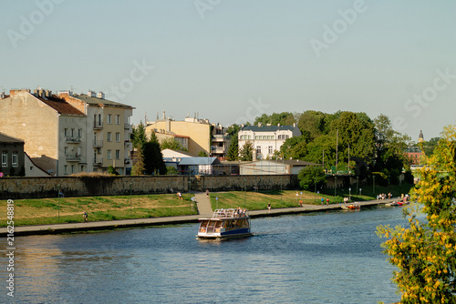 Foto Horizontal riverside cityscape photo of boat on calm water in Krakow, Poland rea