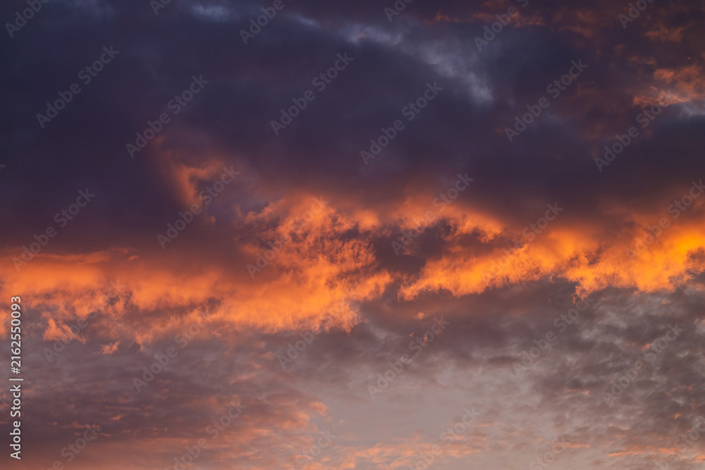 Fototapeta premium Horizontal dramatic sunset cloudscape photo with orange clouds and dark sky real life photography