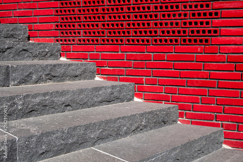 Modern steps in granite and red tile wall outdoors.