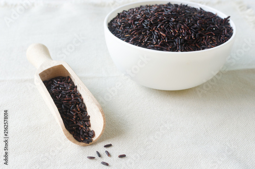 Fotografie Organic Black Rice in a white bowl with a wooden spoon on a light wooden table
