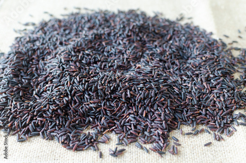 Foto Organic Black Rice scattered on a burlap napkin