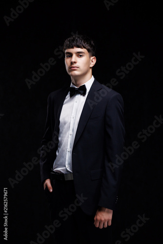 Success and luxury lifestyle, young man in formal tuxedo and bowtie for gala event or corporate award ceremony standing on black background, Elegance and sophistication in fashion, masculine